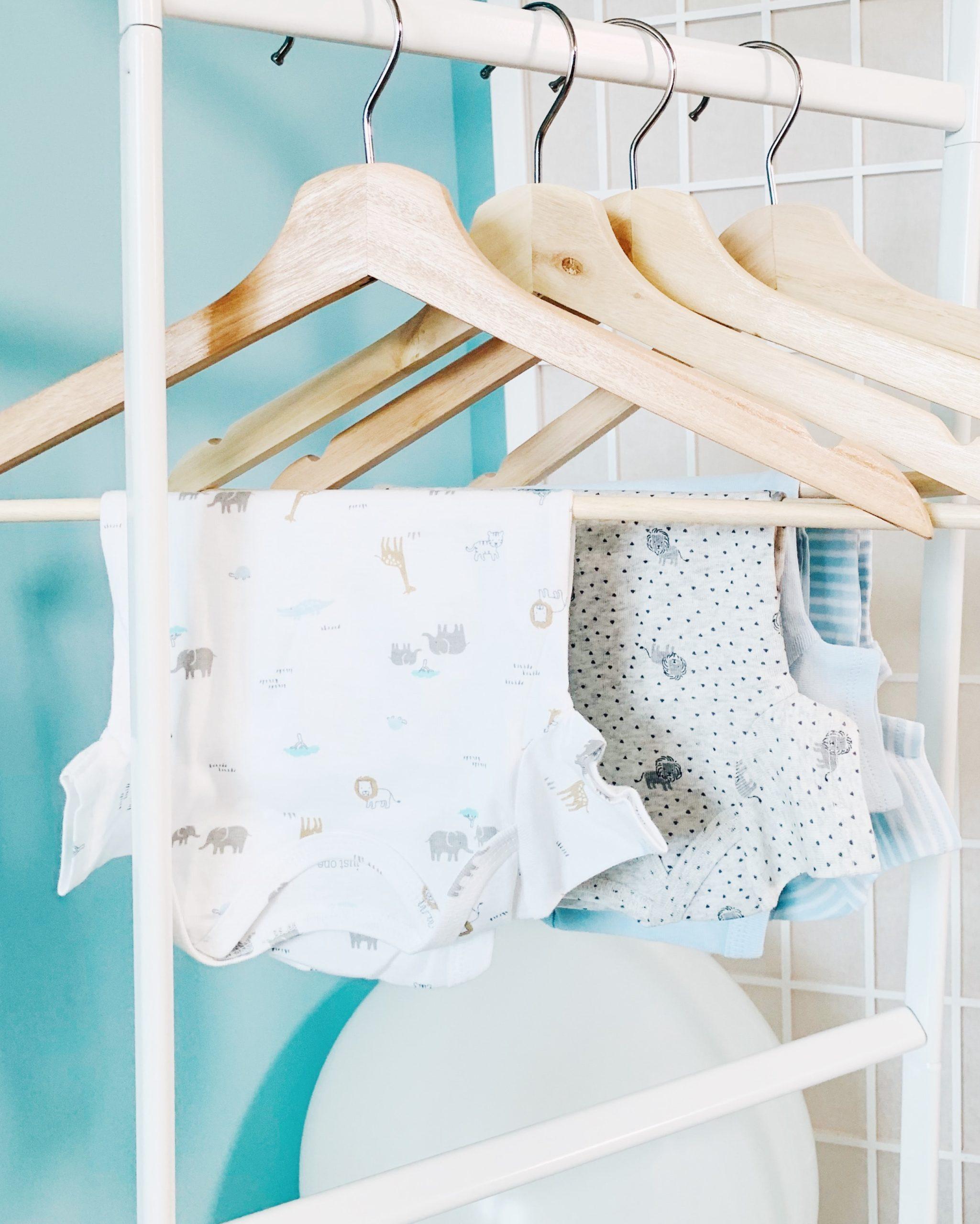 cintres en bois avec body pour bebe, peinture murale bleu-vert