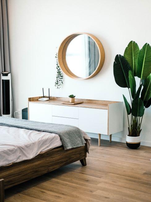 chambre avec lit en bois, meubles blancs et miroir rond