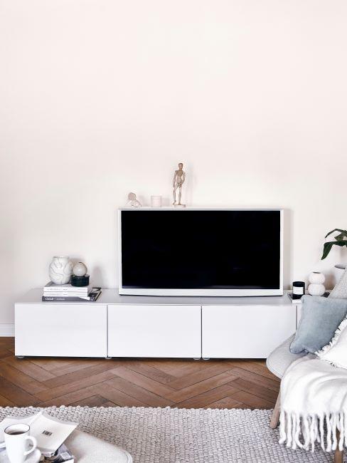 coin tv avec enfilade blanche, tapis beige, fauteuil crème, plaid blanc et coussin bleu