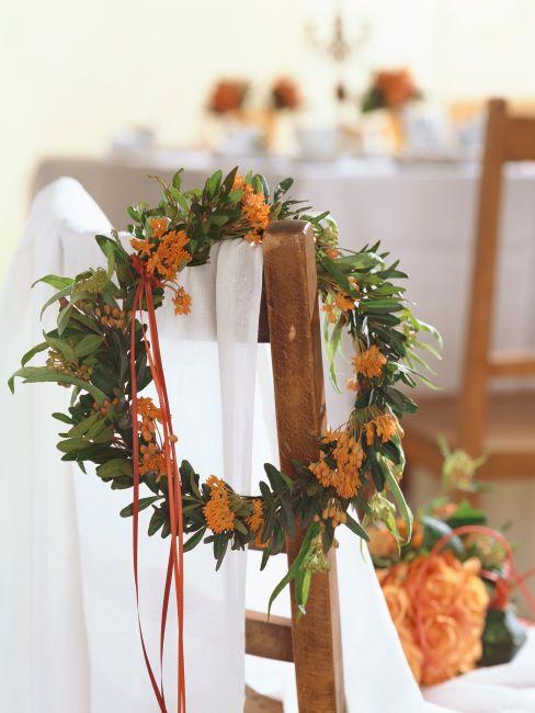 couronne floral orange suspendue sur une chaise en bois