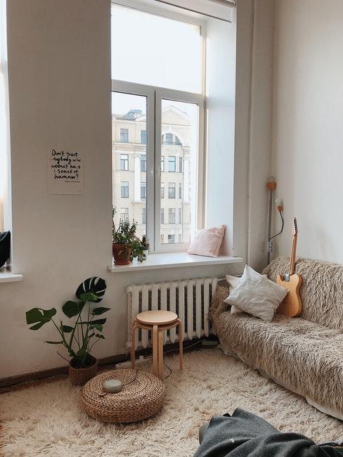 salon haut murs, fenêtre, tapis moelleux, canapé, guitare, tabouret et plantes vertes