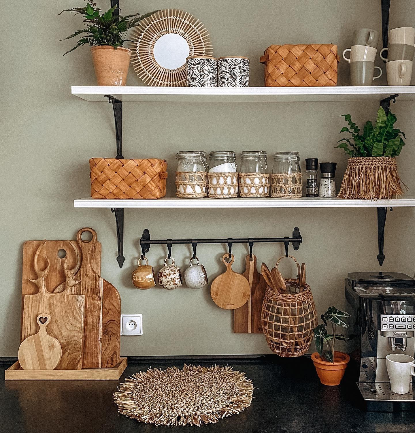 plan de travail de cuisine avec mur couleur vert sauge, étagères avec déco et bocaux, planches à découper en bois et machine à café