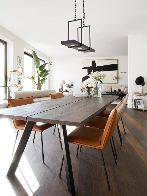 Salle à manger industrielle avec grande table en bois et chaises en cuir