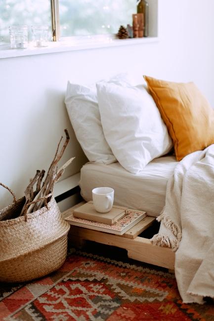 Chambre à coucher épurée avec tapis vintage, corbeille et coussin orange