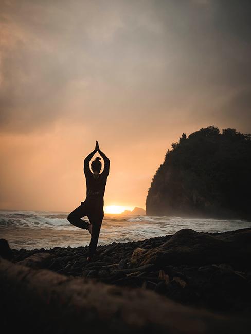 Femme entrain de pratiquer une posture de yoga sur la plage