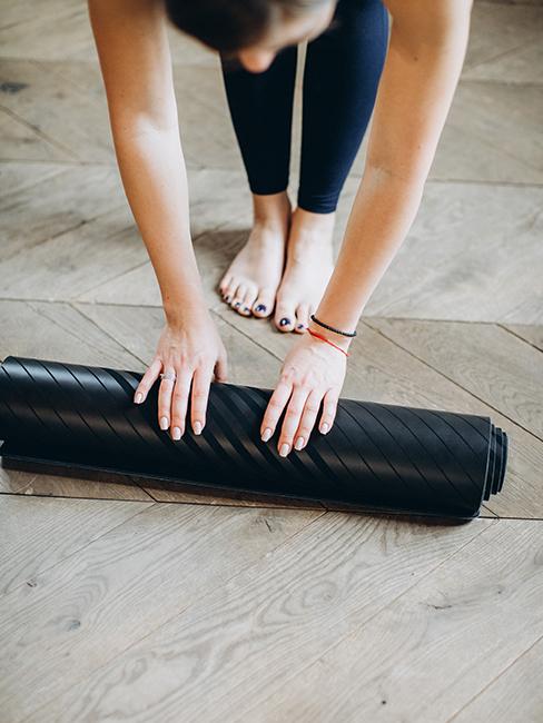 Femme entrain de dérouler un tapis de yoga