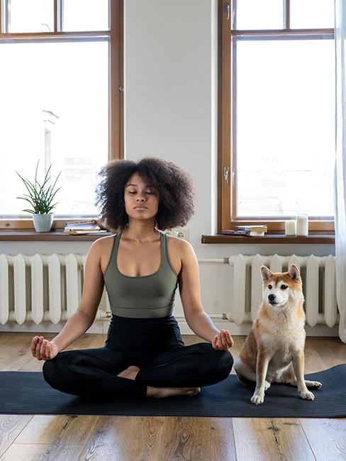 Femme entrain de pratiquer une posture de yoga avec son chien