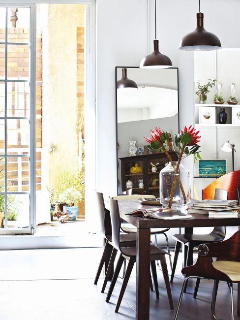 salle à manger avec miroir, meuble en bois foncé, fleur et suspensions de style industriel