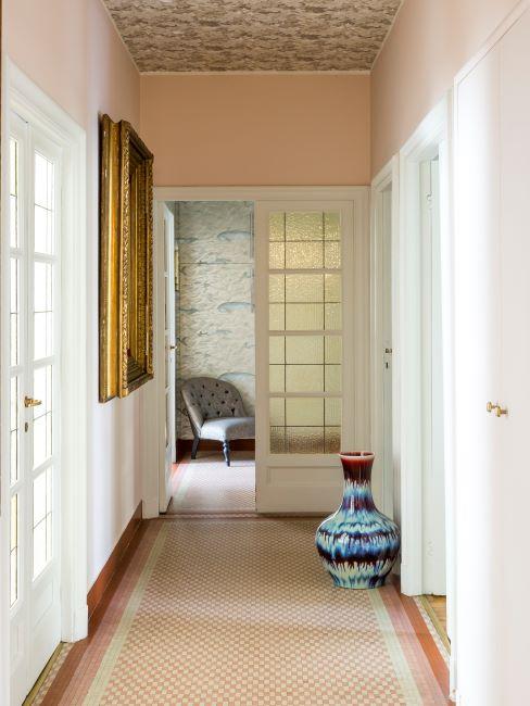 couloir couleur pêche, portes blanches style classique, vase décoratif