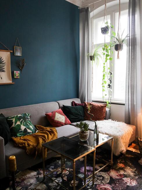 petit salon avec mur de couleur vert sauvage et fauteuil d'angle avec coussins colorés et plantes suspendues