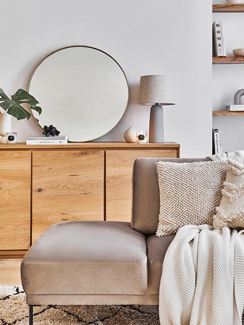 miroir rond posé sur un buffet en bois avec un canapé beige