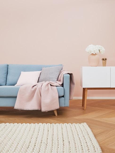 Salon avec mur couleur rose poudre, coussins et plaids