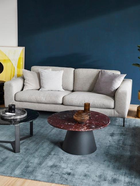 Salon avec peinture murale bleu foncé, tapis bleu doux et canapé gris