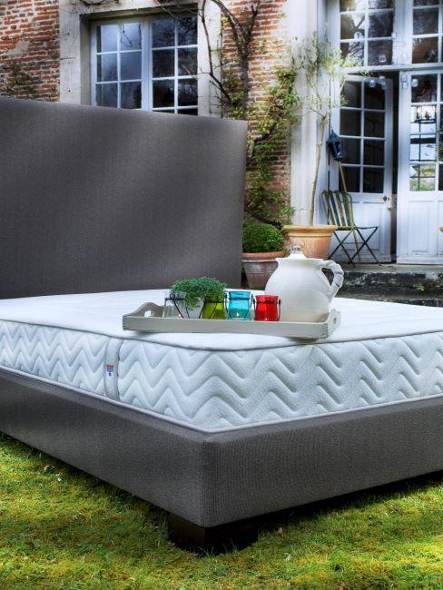 lit matelas tapissier avec un plateau posé dessis, lit situé sur la pelouse devant une maison