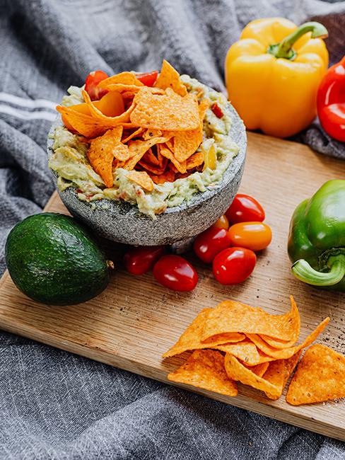 Plat de nachos avec guacamole maison posé sur une planche en bois