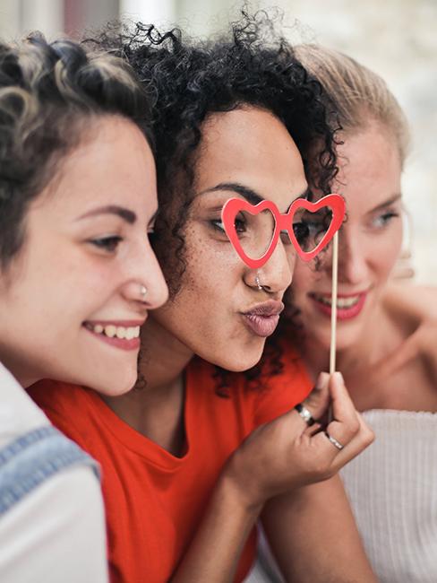 Trois filles entrain de se prendre en photo avec un accessoire de photobooth