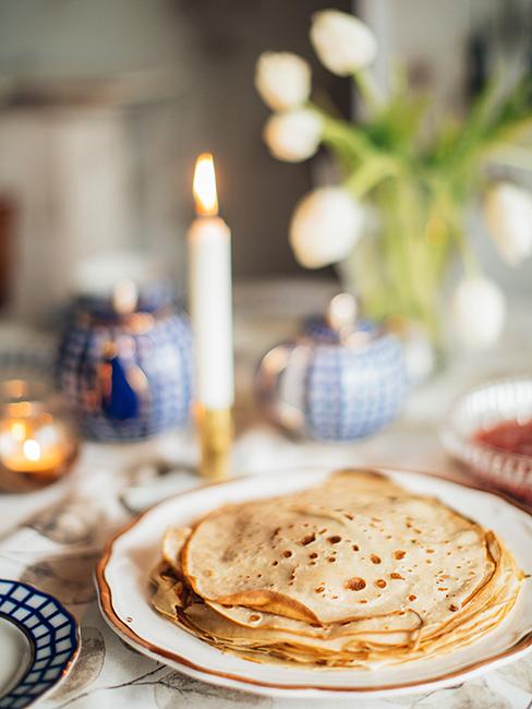 Crêpes dans une assiette posée sur une table avec une bougie