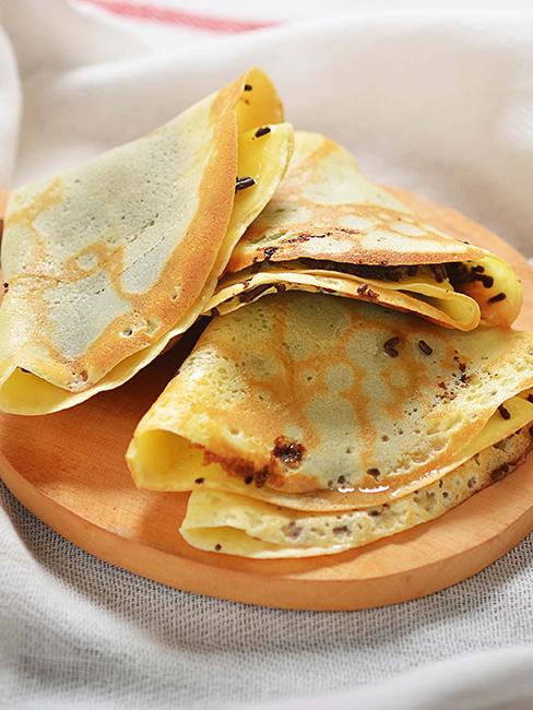 Crêpes pliées en triangle sur un plat rond en bois