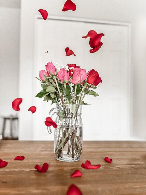 bouquet de roses dans un verre transparent sur une table en bois