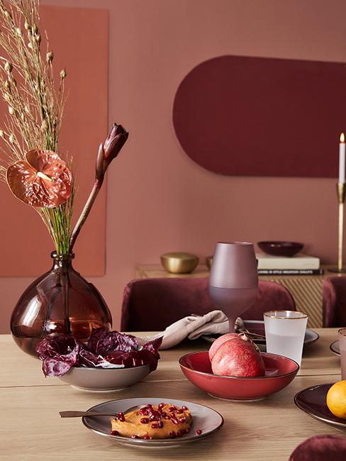 Table en bois avec vaisselle dépareillée et mur corail