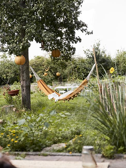 jardin avec hamac jaune accroché à un arbre planté au sol