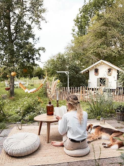 une personne entrain de lire dans son jardin avec son chien