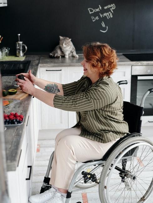 Femme dans sa cuisine, comptoirs blancs et peinture ardoise sur les murs
