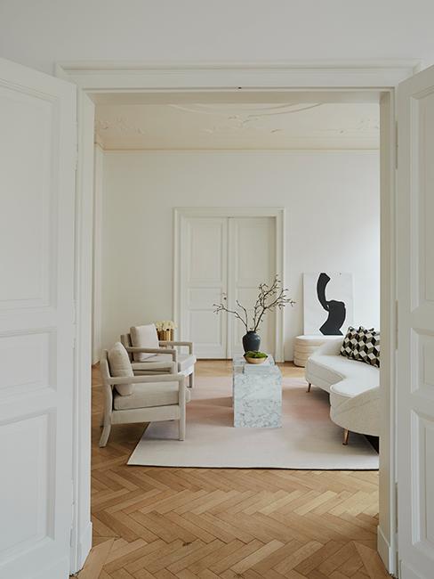 salon avec déco vintage, canapé courbé, fauteuil beige et tapis beige