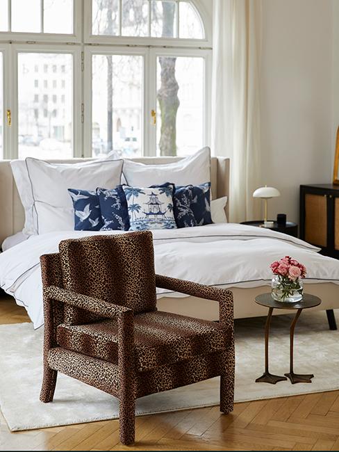 chambre style vintage chic avec fauteuil avec motif animalier, coussins style oriental et linge de lit blanc