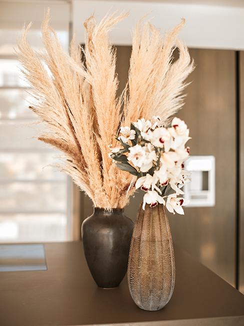 2 vases posés sur une table avec des fleurs et de l'herbe de pampa