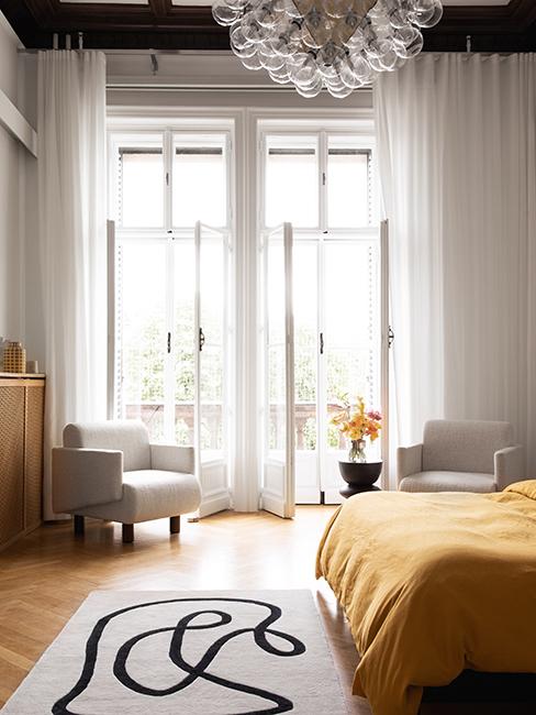 chambre avec linge de lit jaune, fauteuil blanc et tapis graphique westwing collection retro artsy