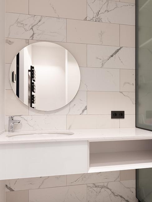 salle de bain avec miroir rond et mur effet marbre