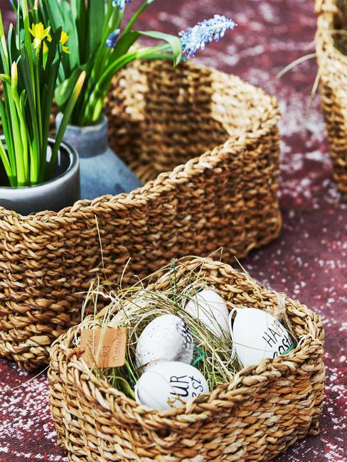 panier en osier avec oeufs de pâques et panier avec plantes de printemps