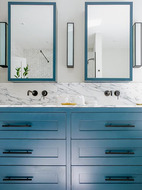 salle de bain avec mur effet marbre, meubles bleus et miroirs
