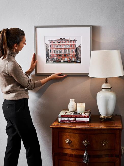 personne entrain d'accrocher un cadre