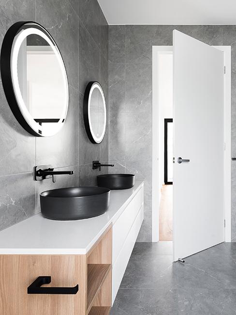 salle de bain moderne grise avec miroirs ronds et éclairage intérieur intégré au miroir