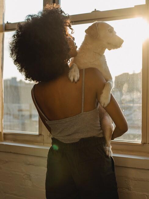 femme avec un chien dans les bras à ola fenêtre d'un appartement