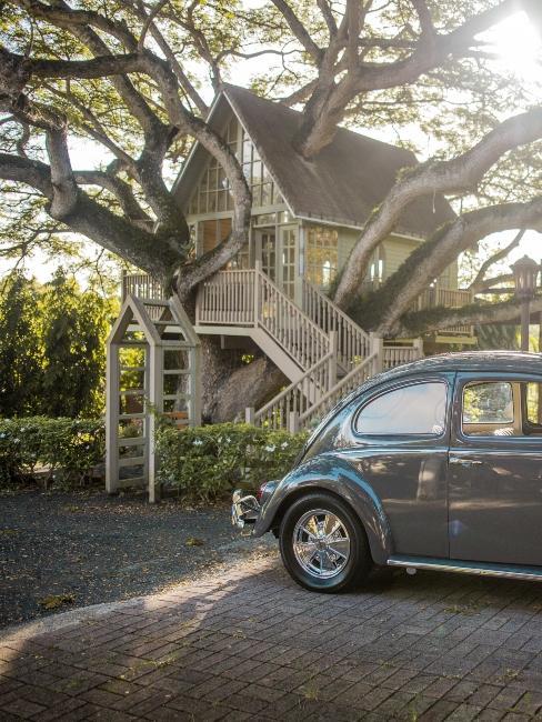 voiture vintage et cabane dans les arbres dans le jardin devant la maison