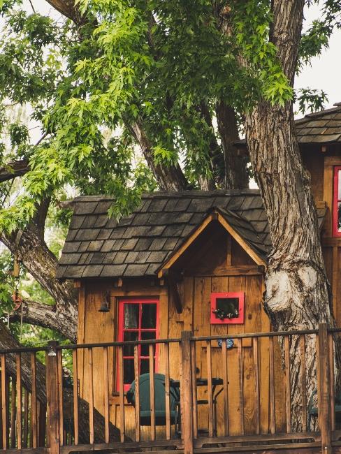 cabane dans les arbres avec fenêtres et portes rouges