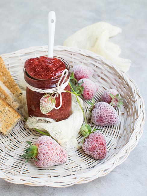 confiture dans un pot en verre faite maison disposé dans un petit plat en osier
