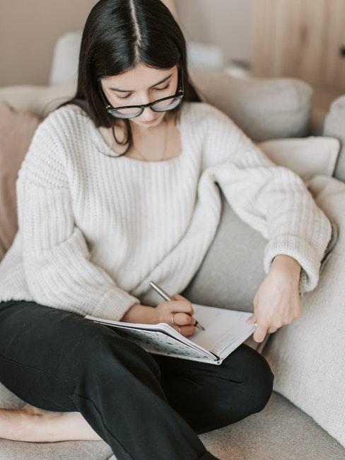 Femme assise sur le canapé dans le salon avec bullet journal