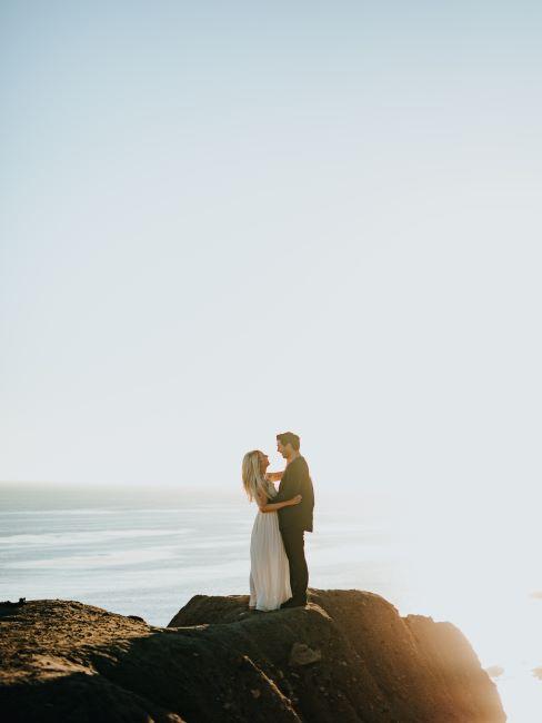 couple de mariés sur une roche avec l'océan dans le paysage