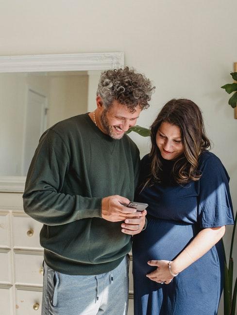 couple homme et femme en train de regarder le téléphone portable, la femme est enceinte