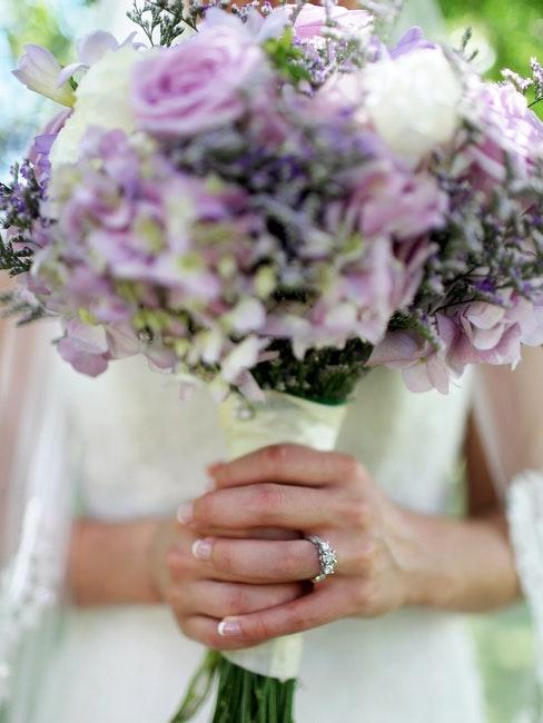 mains d'une mariée enlaçant un bouquet de fleurs