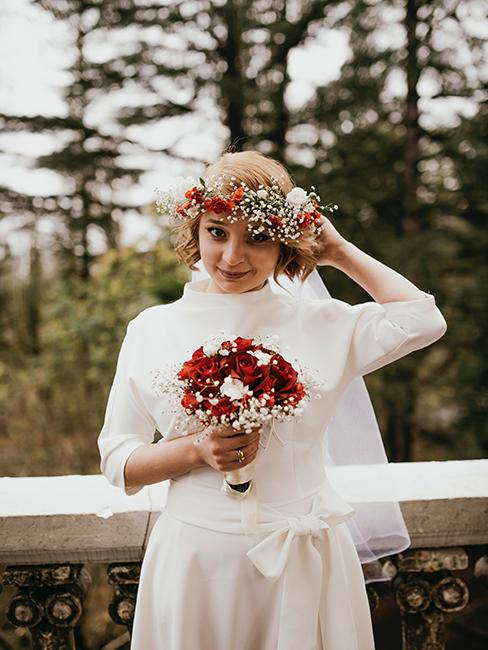 mariée habillée avec une robe longue et une courronne de fleurs rouges et blanches idéale pour un mariage en hiver