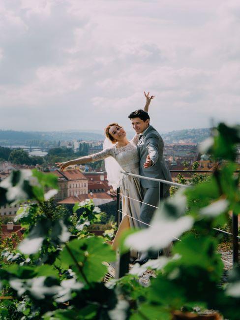 un couple de jeunes mariés sur un balcon, avec une belle vue sur une ville et les montagnes à l'horizon