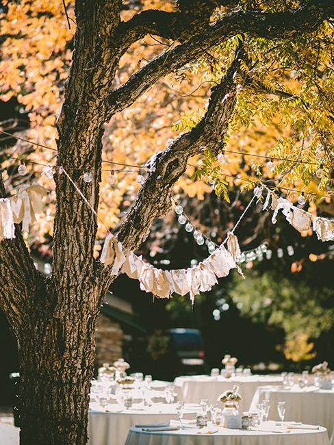 mariage dans un jardin avec table blanche et guirlandes accrochées aux arbres