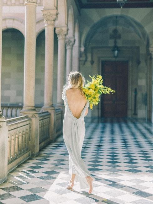 mariée avec bouquet de fleurs dans un couloir de château
