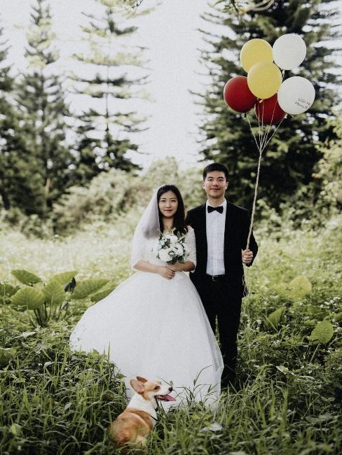 couple de mariés avec ballons dans la forêt
