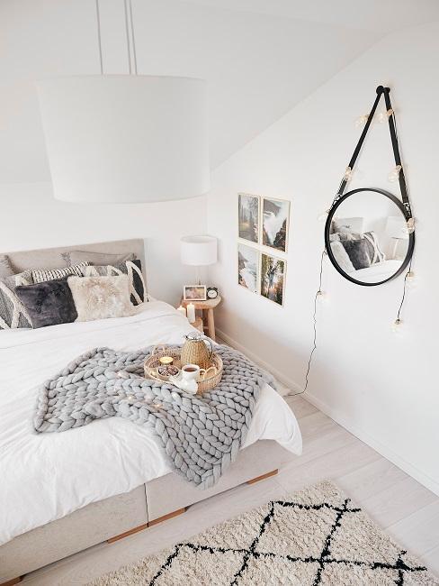 petite chambre avec miroir mural rond décoré de guirlandes lumineuses, plaid gris grosse maille